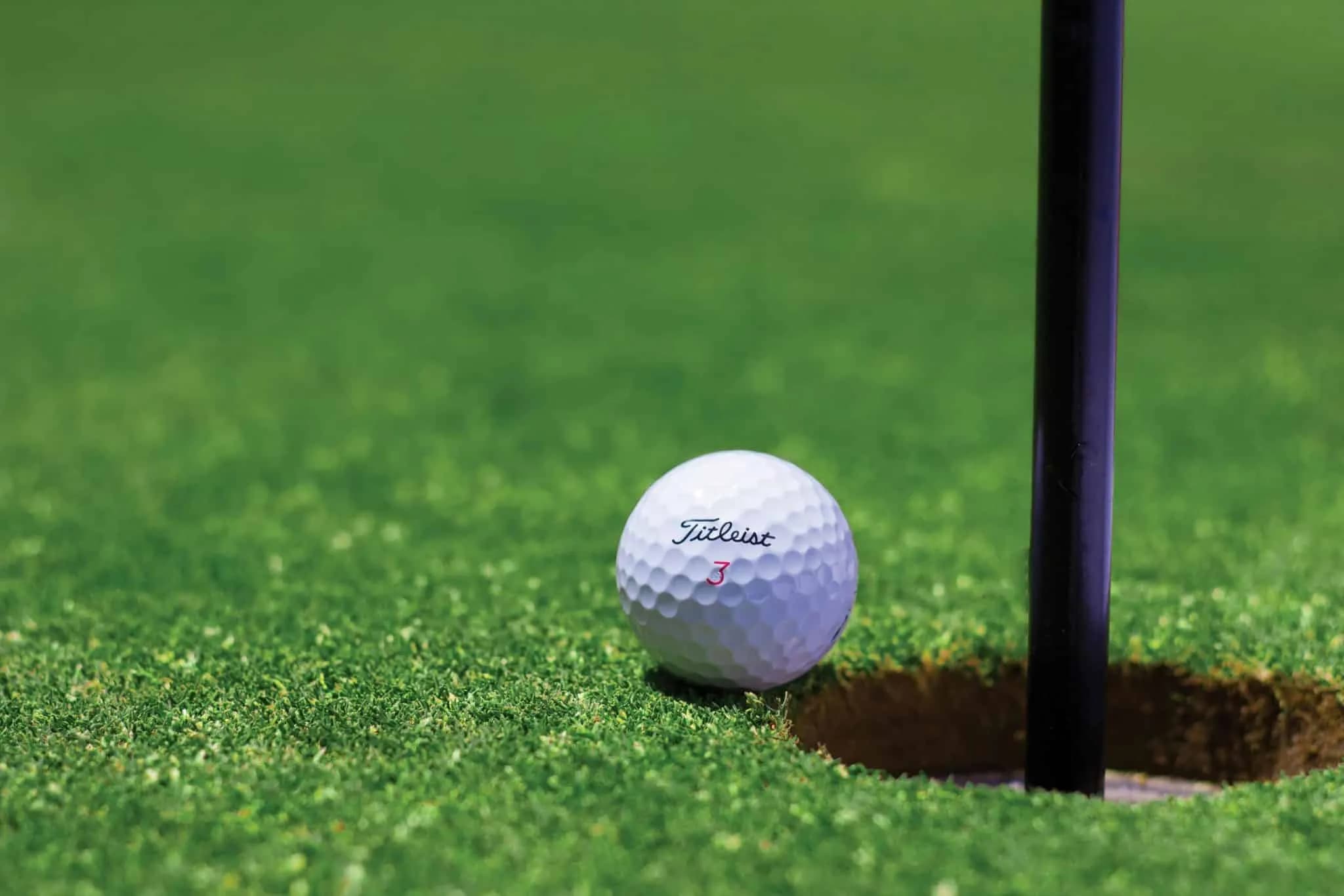 Golf ball next to hole on golf course