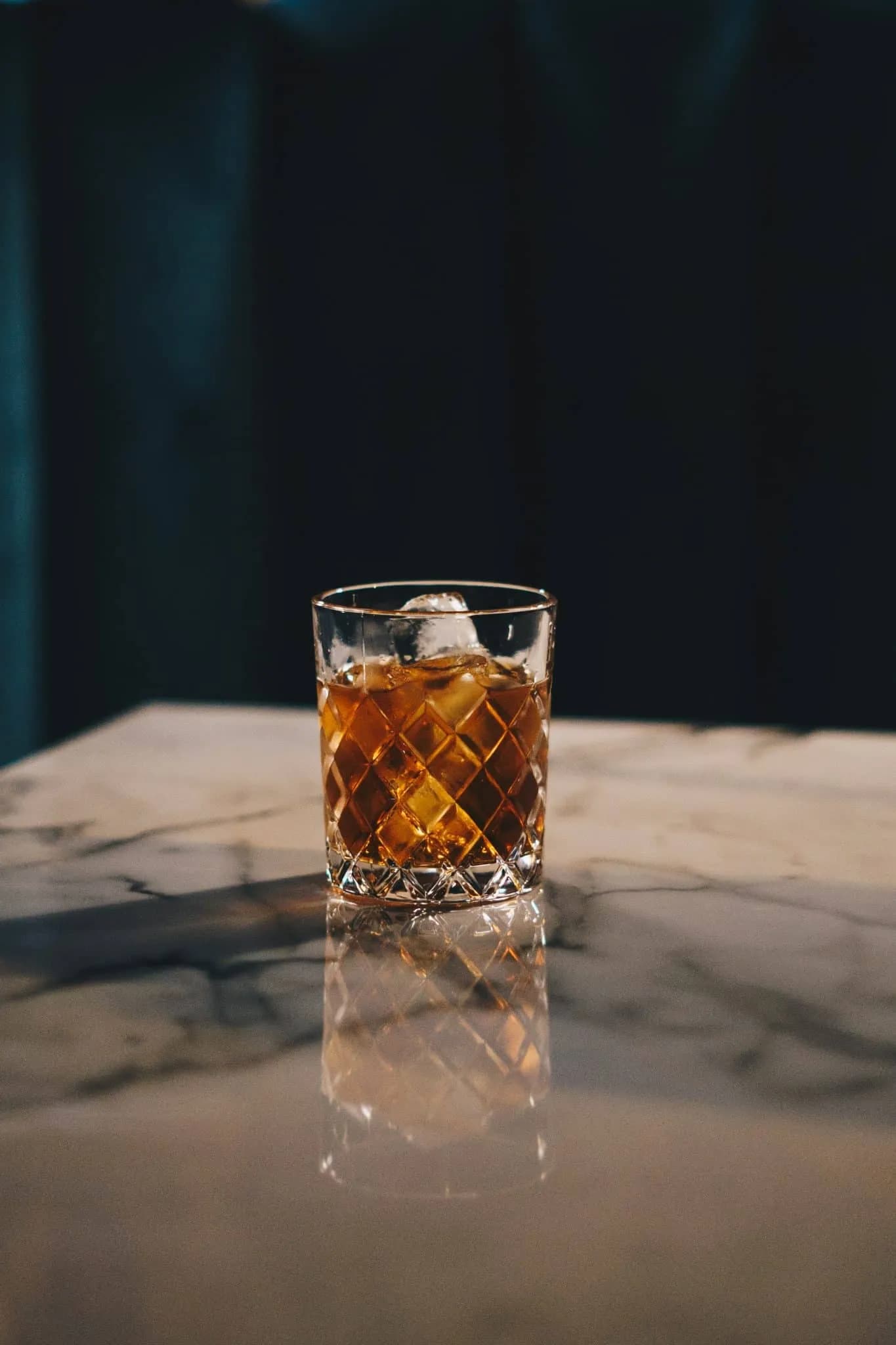 Glass of whiskey sitting on top of marble counter
