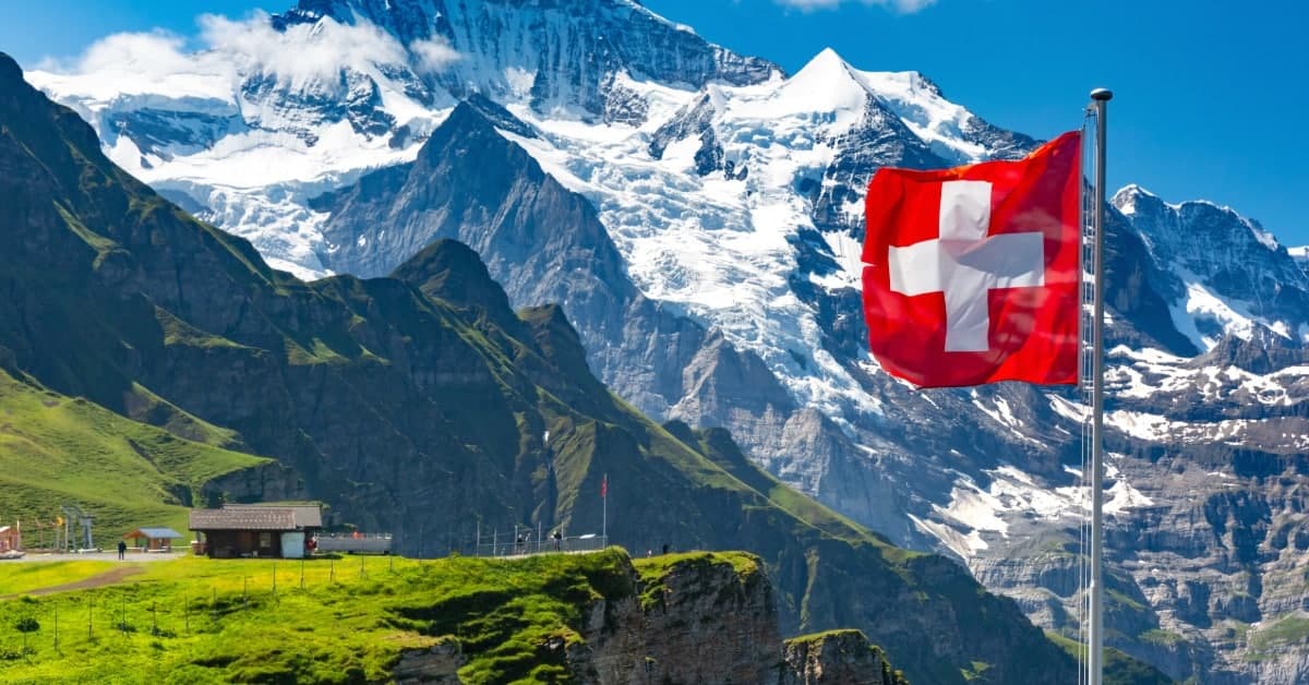 A beautiful mountain view on a sunny day in Switzerland. The county's red flag waves in the foreground.