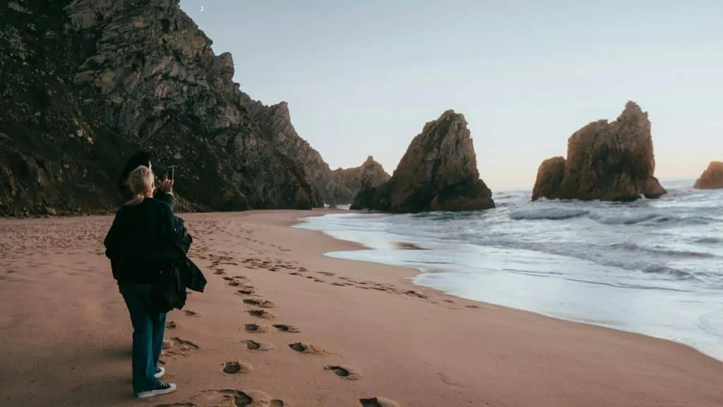 A Couple walking along the Praia Da Ursa Beach