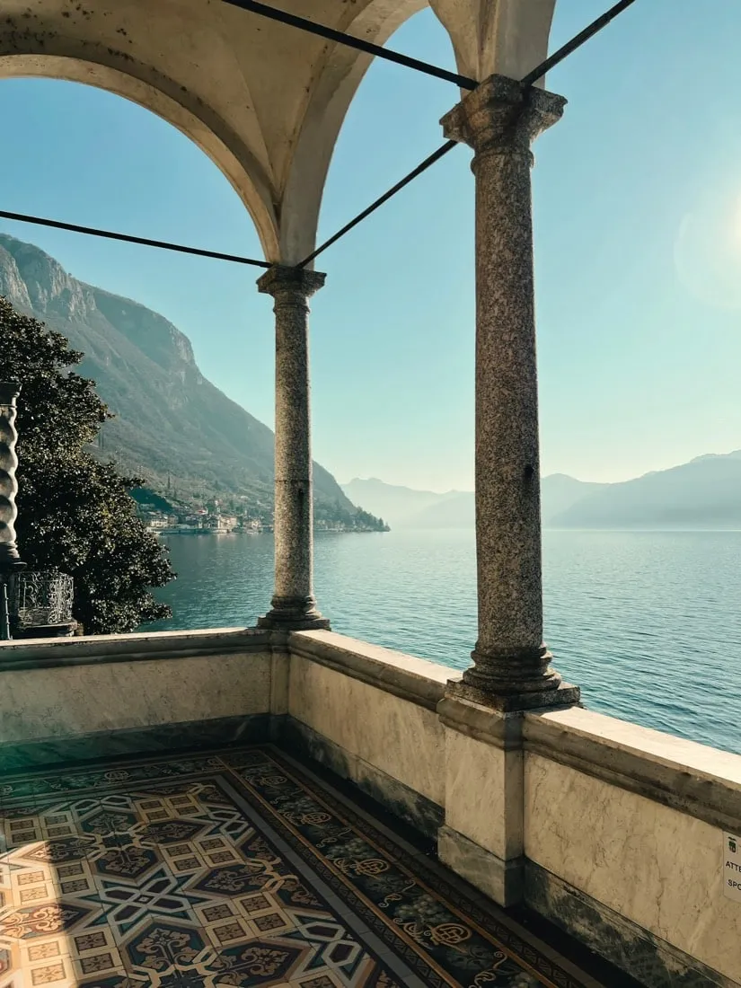 View of Lake Como and the surrounding mountains from the arched stone loggia of a historic lakeside villa