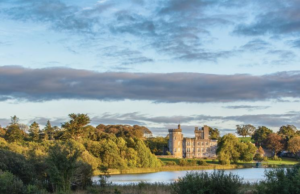 Overlooking a large pond surrounded by green trees and landscape is a castle
