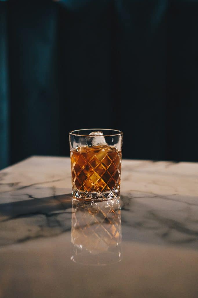 Glass of whiskey sitting on top of marble counter 