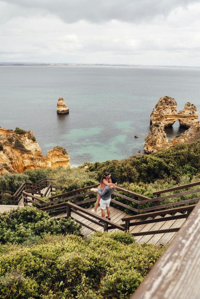 A Couple Kissing while on the Cliff overlooking ocean and rock formations in Faro District, Portugal