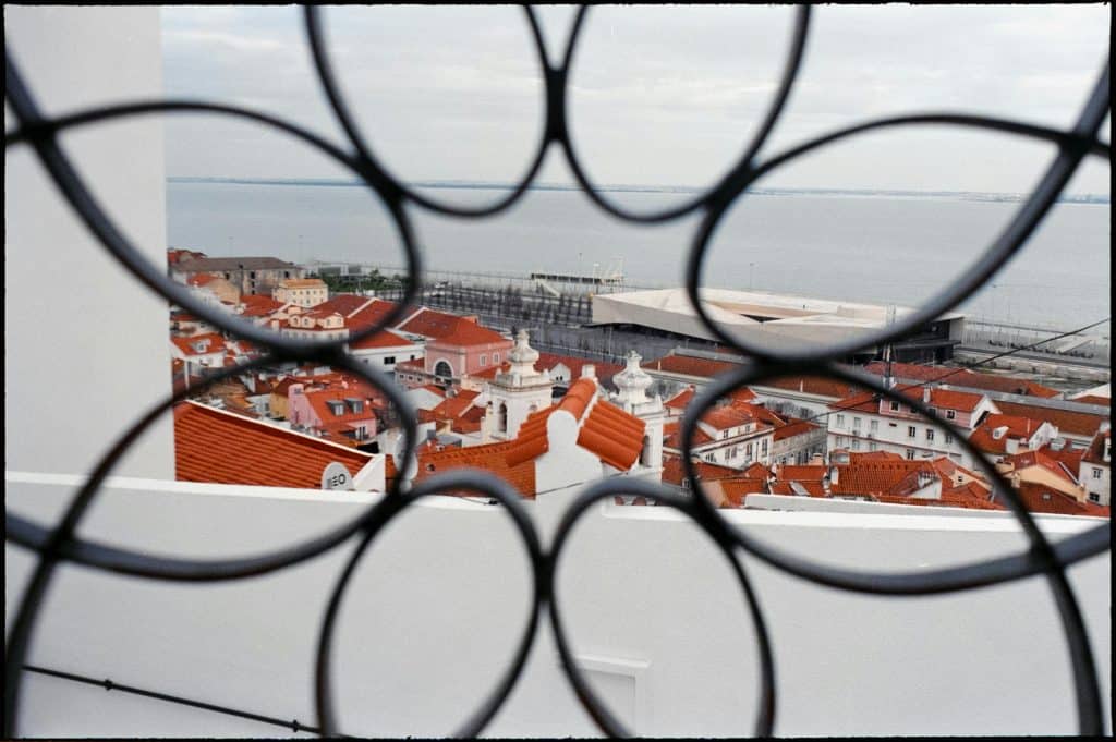 Red Rooftops of Lisbon Seen through Metal Railing