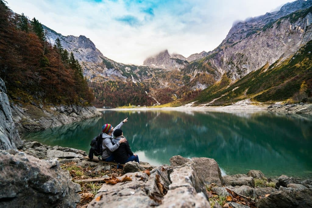 Couple Sitting on Rock Beside Lake in Hallstatt, Upper Austria, Austria