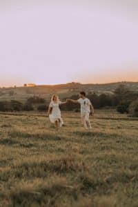 Couple Holding Hands Up Together on a Grass Field