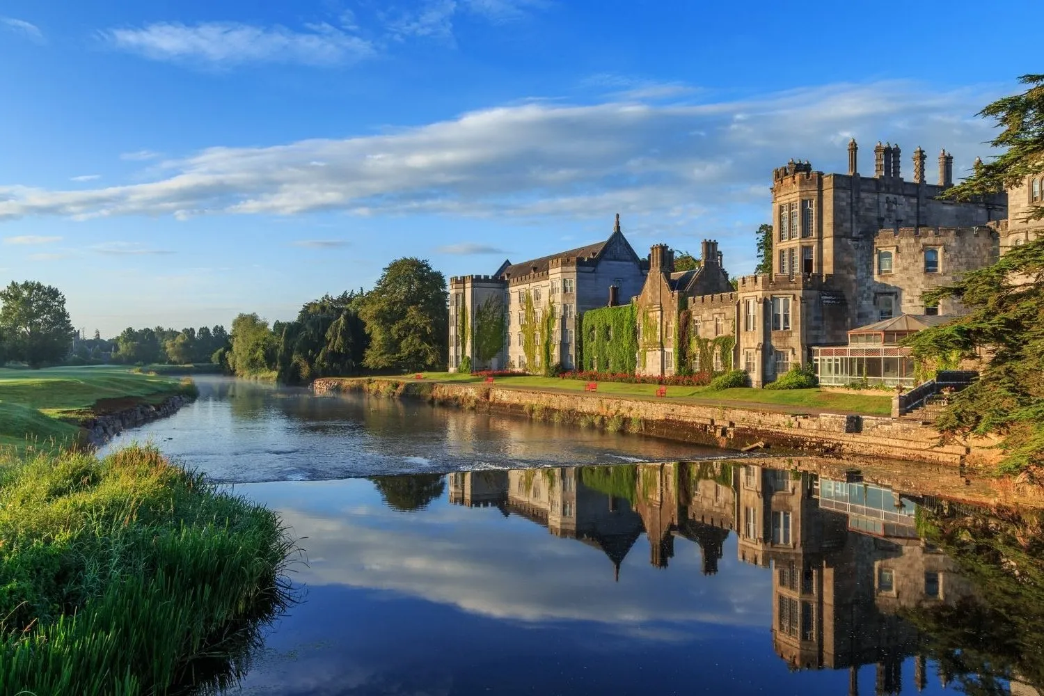 A castle hotel reflected in its river at first light — private castle stays on a Juniper Tours Ireland trip